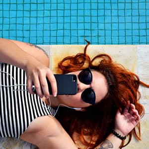 Young woman eating ice cream by swimming pool